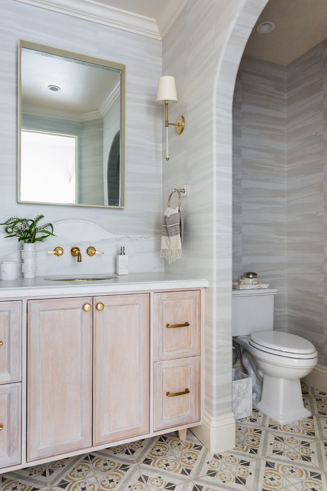 Small mediterranean powder room in Los Angeles with light wood cabinets, cement tiles, an undermount sink, marble benchtops, white benchtops, recessed-panel cabinets, a two-piece toilet, grey walls and multi-coloured floor.