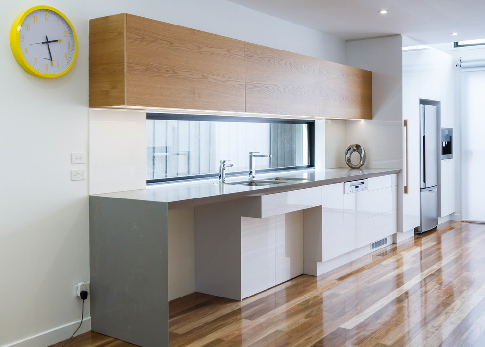 Inspiration for a large modern galley open plan kitchen in Melbourne with an undermount sink, flat-panel cabinets, quartz benchtops, medium hardwood floors and no island.