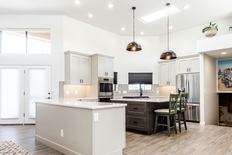 Inspiration for a large transitional u-shaped vinyl floor and gray floor eat-in kitchen remodel with an undermount sink, shaker cabinets, gray cabinets, quartzite countertops, green backsplash, subway tile backsplash, stainless steel appliances, an island and white countertops