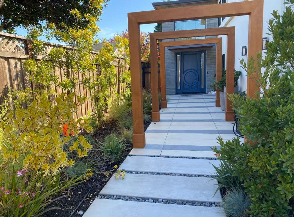 Design ideas for a mid-sized contemporary front yard partial sun xeriscape for spring in San Francisco with with path, concrete pavers and a wood fence.