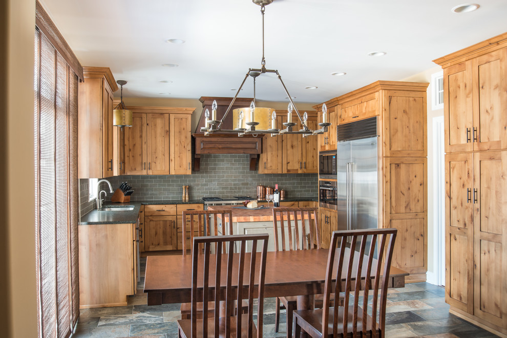 Mid-sized country u-shaped eat-in kitchen in Chicago with an undermount sink, shaker cabinets, distressed cabinets, granite benchtops, grey splashback, ceramic splashback, stainless steel appliances and porcelain floors.