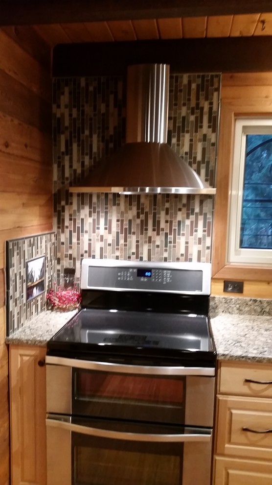 Mid-sized mountain style u-shaped medium tone wood floor enclosed kitchen photo in Seattle with an undermount sink, raised-panel cabinets, light wood cabinets, granite countertops, multicolored backsplash, matchstick tile backsplash, stainless steel appliances and a peninsula