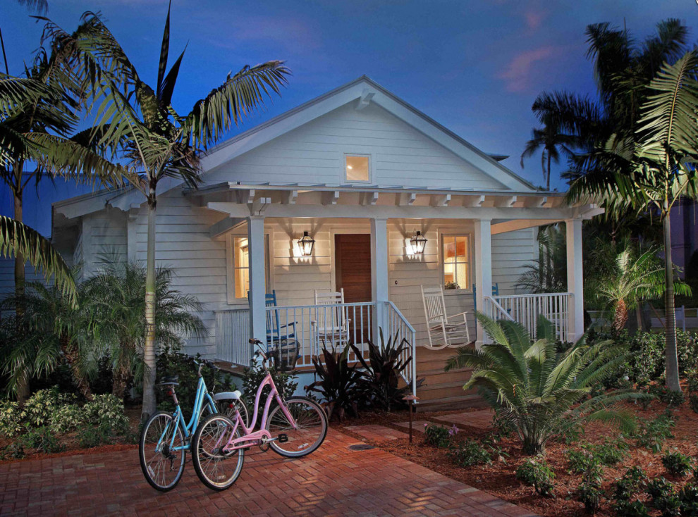Small beach style one-storey white house exterior in New Orleans with mixed siding and a metal roof.