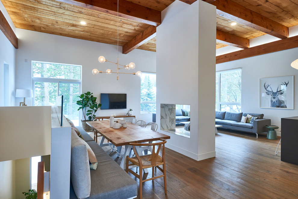 Photo of a scandinavian open plan dining in Toronto with white walls, light hardwood floors and a two-sided fireplace.