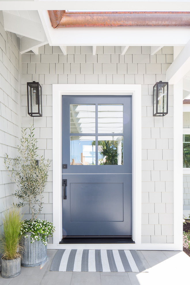 Inspiration for a beach style front door in Orange County with grey walls, porcelain floors, a dutch front door, a blue front door and grey floor.