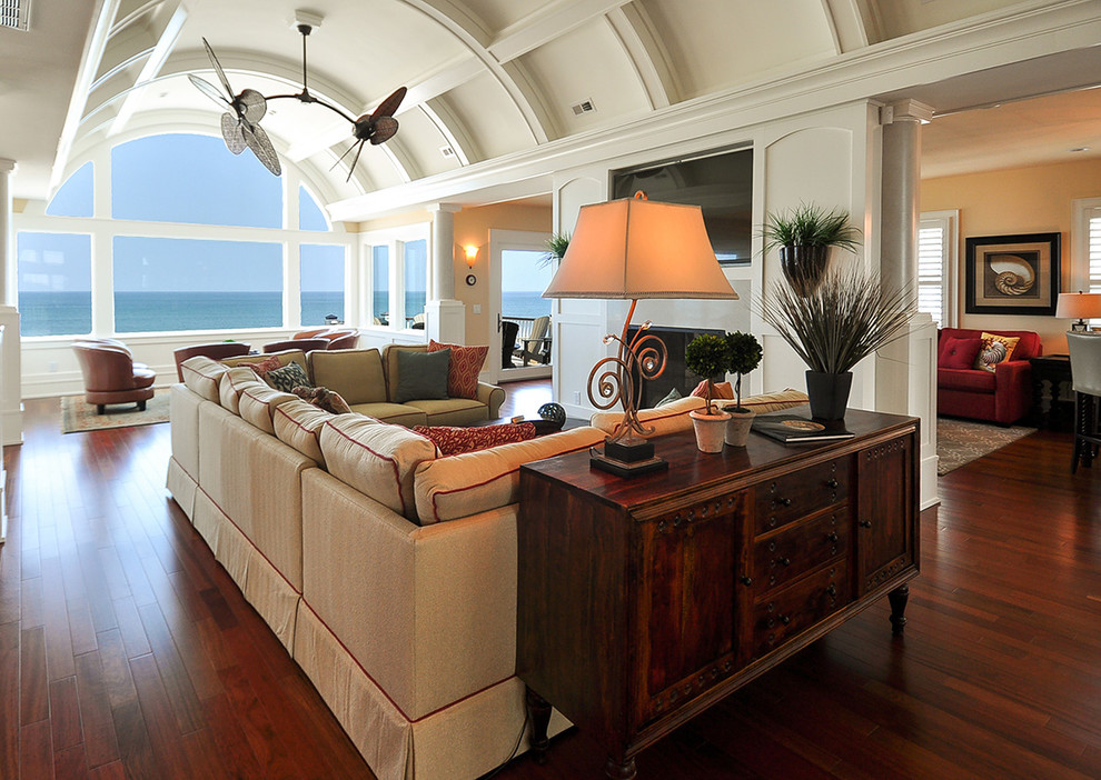 Photo of a mid-sized beach style open concept family room in Other with white walls, dark hardwood floors, a standard fireplace, a tile fireplace surround and a wall-mounted tv.