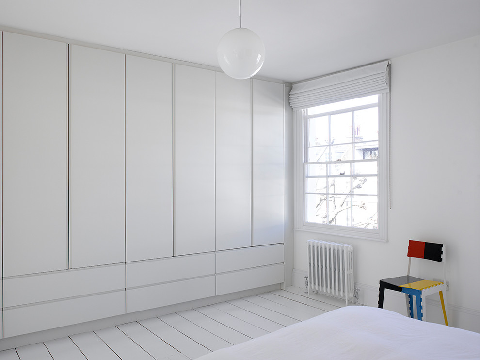 Large contemporary gender-neutral built-in wardrobe in London with flat-panel cabinets, white cabinets, painted wood floors and white floor.