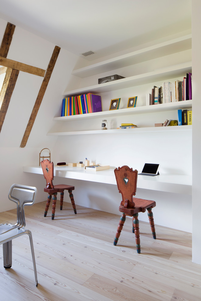 Design ideas for a large contemporary home office in Milan with a built-in desk, exposed beam and light hardwood floors.