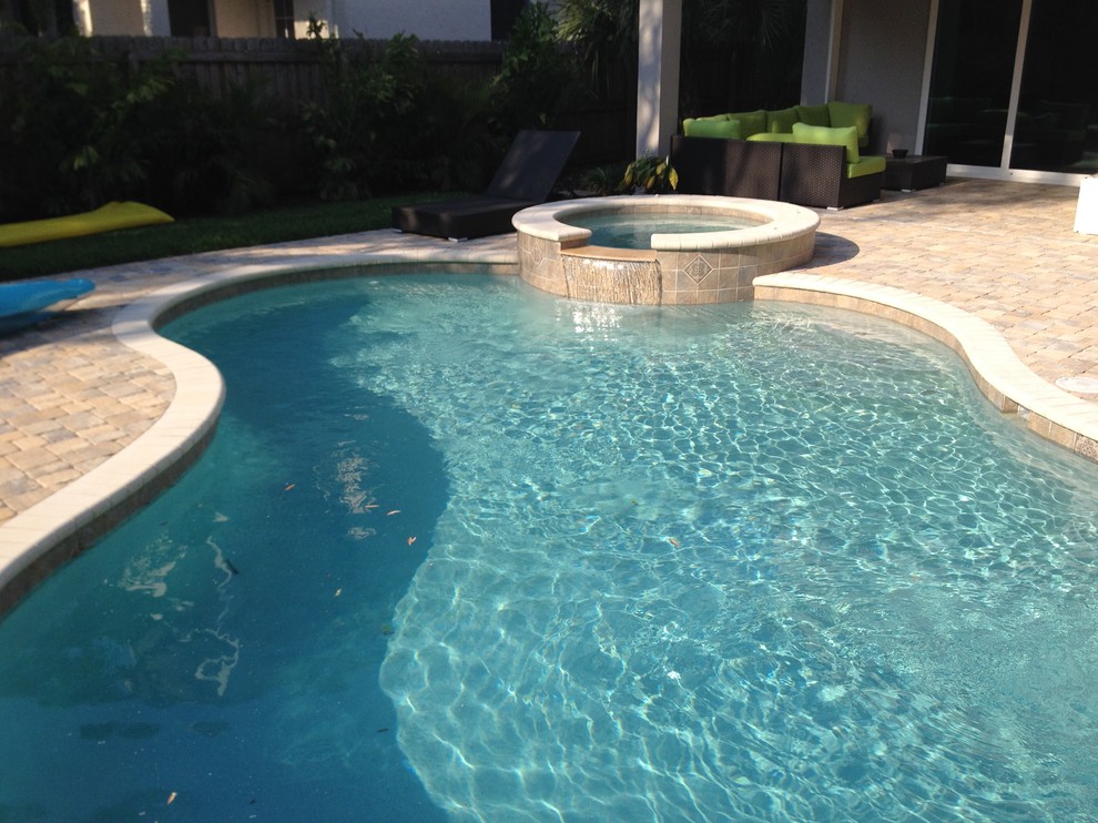This is an example of a small custom-shaped pool in Tampa with brick pavers.