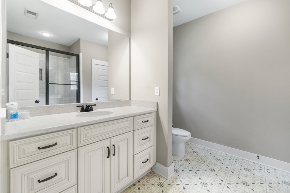 Large country kids bathroom in Atlanta with beaded inset cabinets, beige cabinets, a freestanding tub, an alcove shower, a one-piece toilet, beige tile, beige walls, a drop-in sink, granite benchtops, white floor, a sliding shower screen, white benchtops, a single vanity, a built-in vanity and vinyl floors.