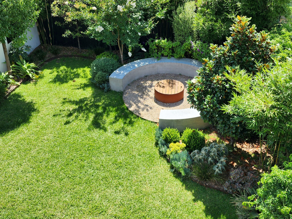 Свежая идея для дизайна: большой солнечный, осенний участок и сад на заднем дворе в современном стиле с местом для костра, хорошей освещенностью, покрытием из каменной брусчатки и с деревянным забором - отличное фото интерьера