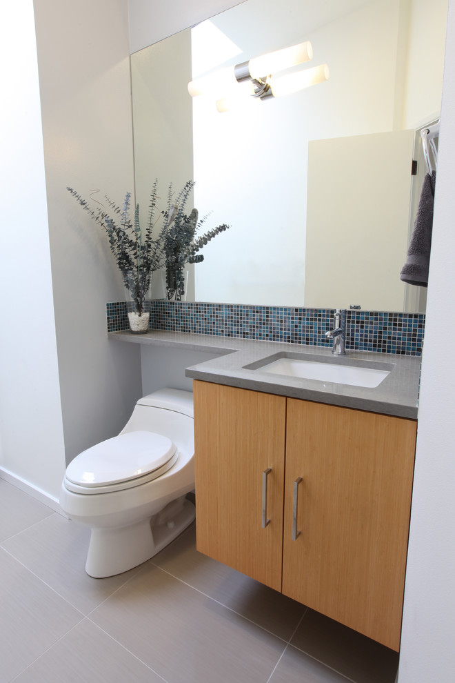 Photo of a mid-sized midcentury 3/4 bathroom in Seattle with flat-panel cabinets, light wood cabinets, an undermount tub, a one-piece toilet, gray tile, porcelain tile, white walls, porcelain floors, an undermount sink, engineered quartz benchtops and an alcove shower.