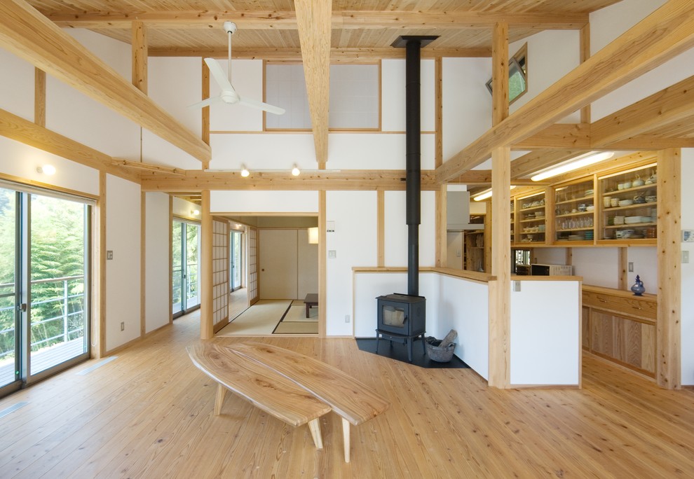 Photo of an asian open concept living room in Tokyo Suburbs with white walls, light hardwood floors, a wood stove, beige floor and a plaster fireplace surround.