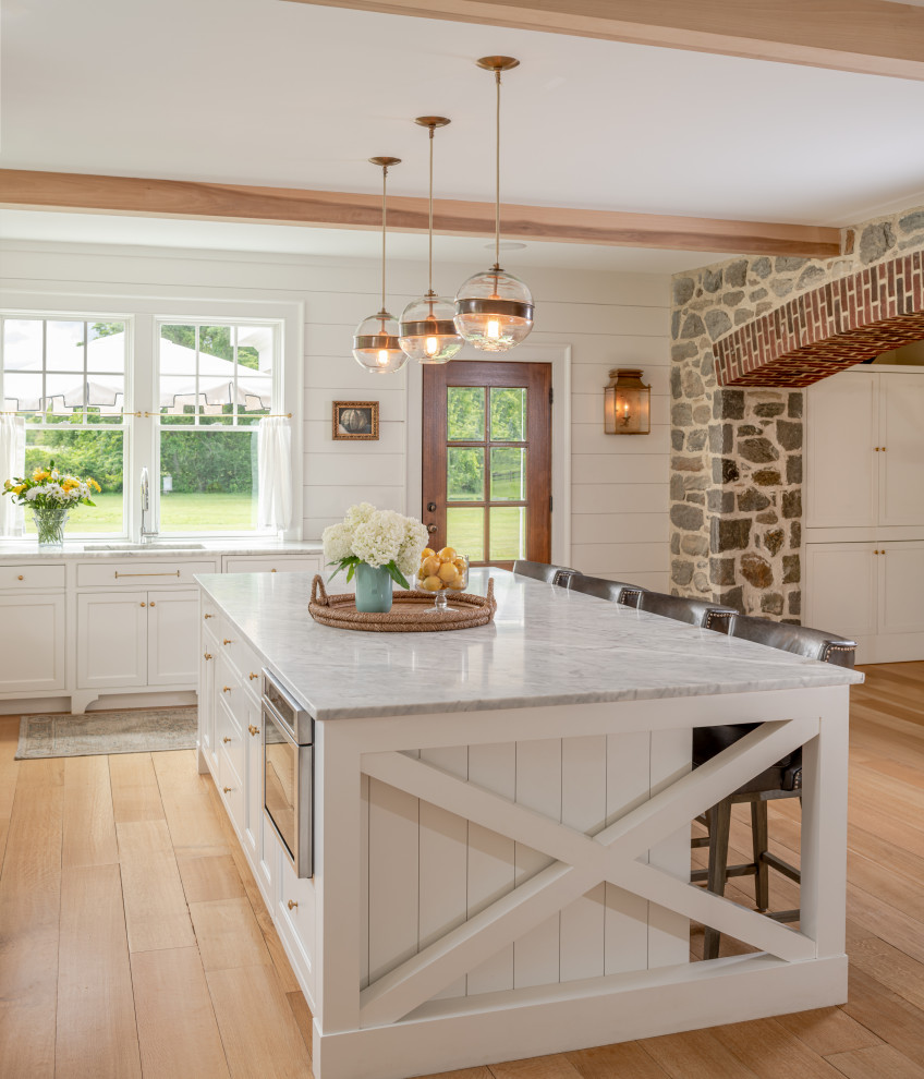 Design ideas for a large country l-shaped open plan kitchen in Philadelphia with an undermount sink, white cabinets, marble benchtops, light hardwood floors, with island, beige floor, grey benchtop, shaker cabinets, white splashback and timber splashback.