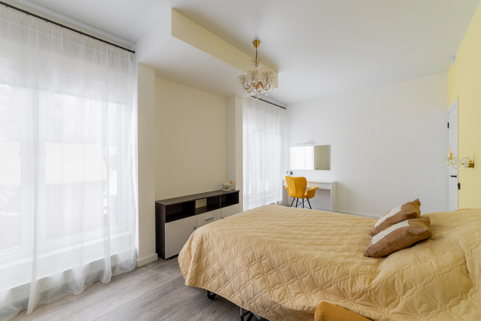 На фото: большая хозяйская спальня в стиле модернизм с желтыми стенами, полом из ламината, коричневым полом, многоуровневым потолком и акцентной стеной без камина с