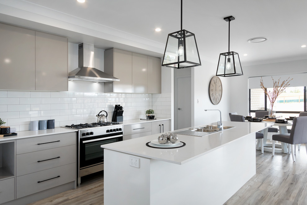 Inspiration for a contemporary galley eat-in kitchen in Brisbane with a double-bowl sink, flat-panel cabinets, grey cabinets, white splashback, subway tile splashback, stainless steel appliances, with island and grey floor.