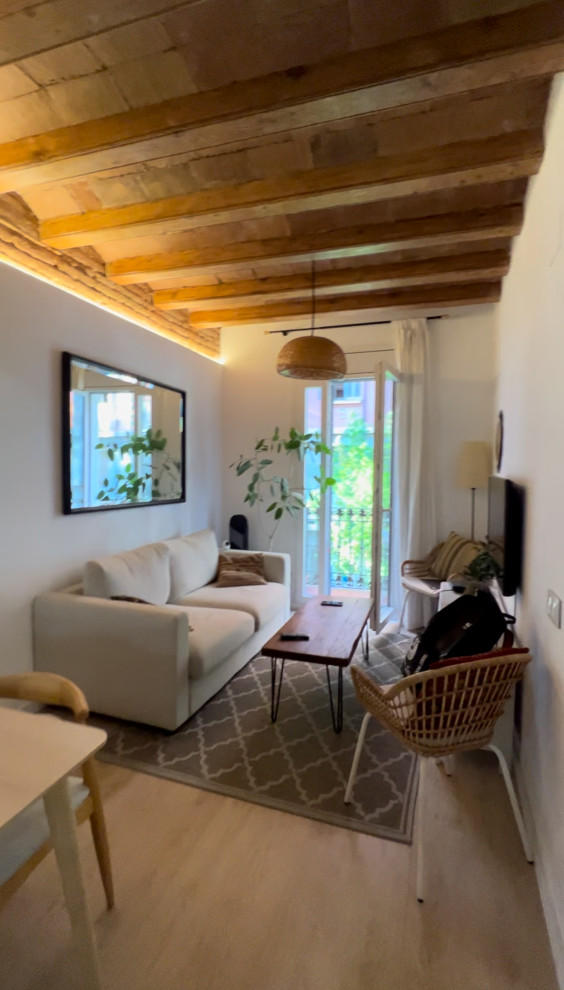 Immagine di un piccolo soggiorno mediterraneo aperto con pareti bianche, parquet chiaro, TV autoportante, pavimento marrone, travi a vista e pareti in mattoni