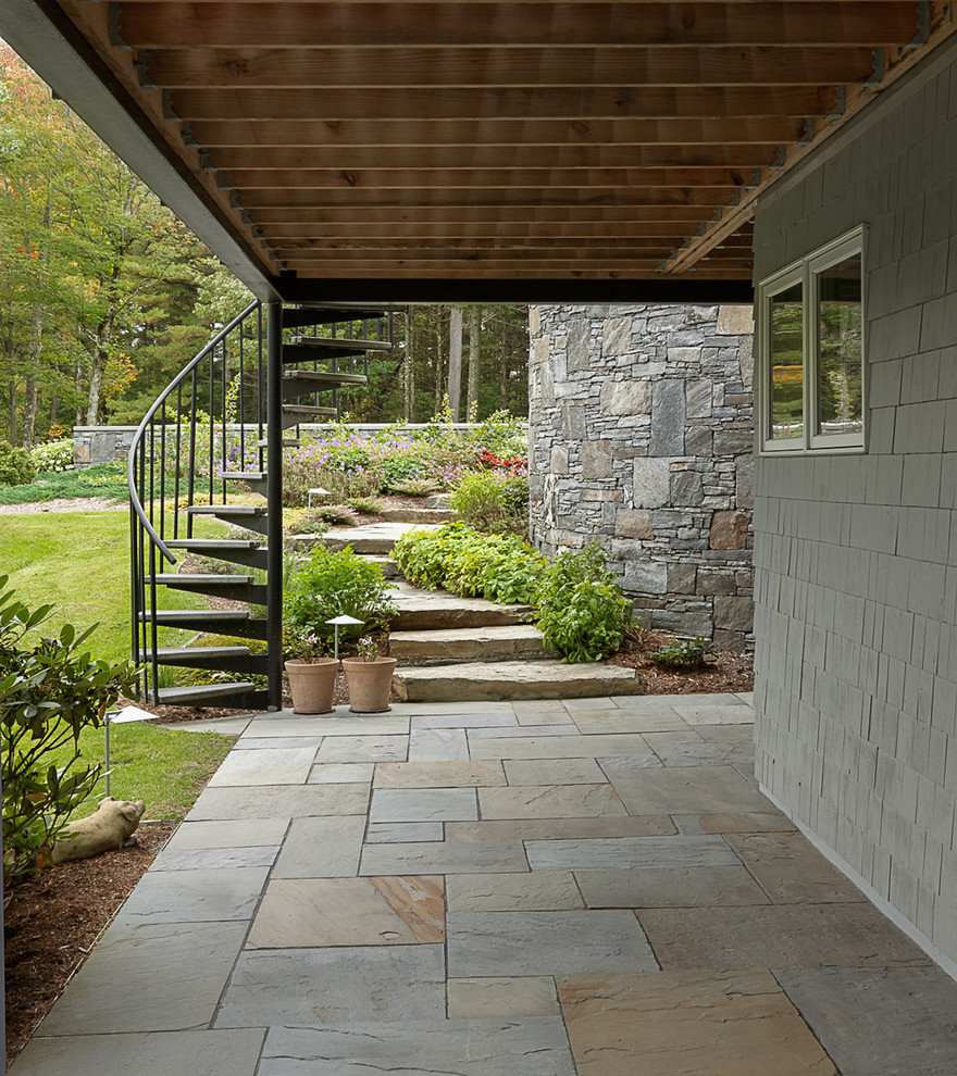 Photo of a large contemporary backyard patio in Burlington with a fire feature, natural stone pavers and a roof extension.