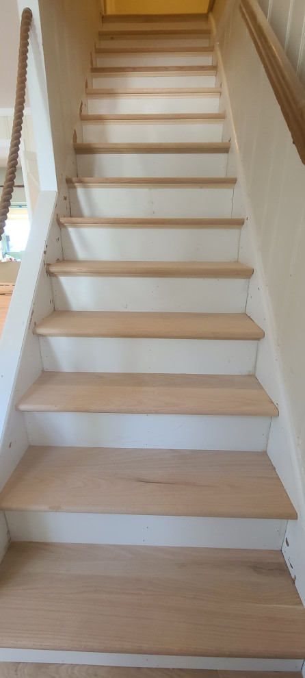 Mid-sized beach style wood straight staircase in New York with wood risers and wood railing.