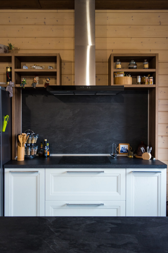 Photo of a large scandinavian u-shaped eat-in kitchen in Other with recessed-panel cabinets, white cabinets, laminate benchtops, black splashback, ceramic splashback, coloured appliances, medium hardwood floors, with island, brown floor and black benchtop.