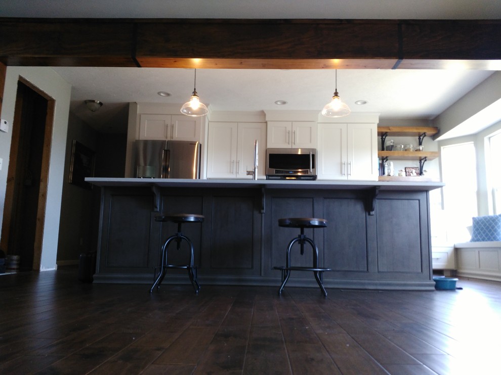 Example of a mid-sized transitional l-shaped dark wood floor and brown floor eat-in kitchen design with a single-bowl sink, shaker cabinets, white cabinets, quartzite countertops, gray backsplash, ceramic backsplash, stainless steel appliances and an island