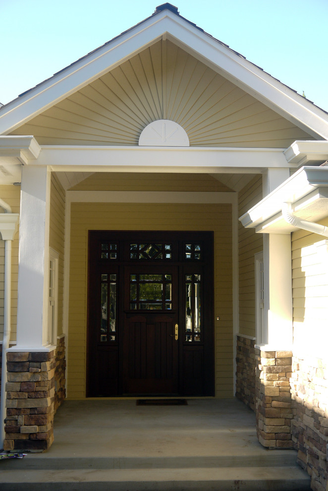 This is an example of a transitional entryway in Other with yellow walls, a single front door and a dark wood front door.