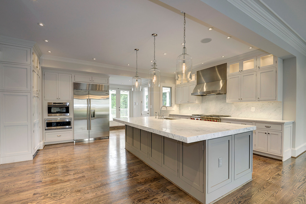 This is an example of a large traditional l-shaped open plan kitchen in DC Metro with an undermount sink, shaker cabinets, grey cabinets, marble benchtops, white splashback, stone slab splashback, stainless steel appliances, medium hardwood floors and with island.