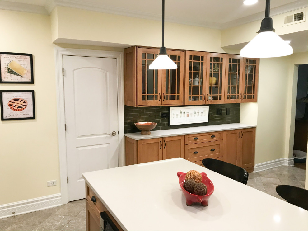 Example of a mid-sized transitional l-shaped eat-in kitchen design in Chicago with an undermount sink, shaker cabinets, brown cabinets, green backsplash, stainless steel appliances, an island and gray countertops