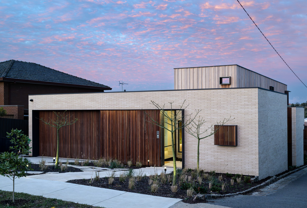Design ideas for a modern two-storey beige house exterior in Melbourne with a flat roof.