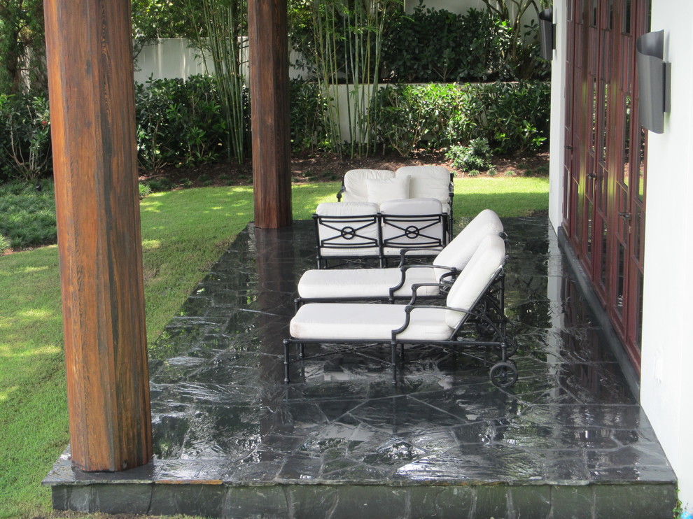 Photo of a contemporary backyard verandah in Miami with natural stone pavers.