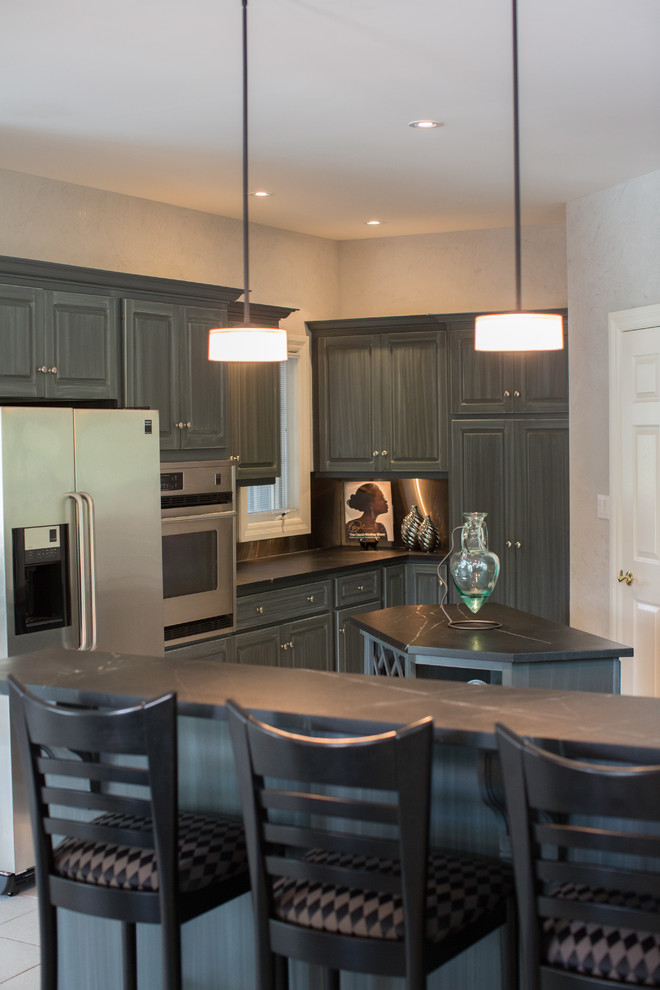 Example of a mid-sized transitional u-shaped ceramic tile enclosed kitchen design in Toronto with an undermount sink, raised-panel cabinets, blue cabinets, soapstone countertops, metallic backsplash and an island