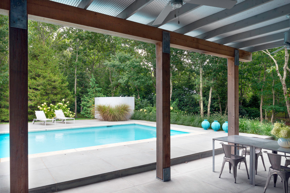 This is an example of a small contemporary backyard rectangular pool in New York with natural stone pavers.