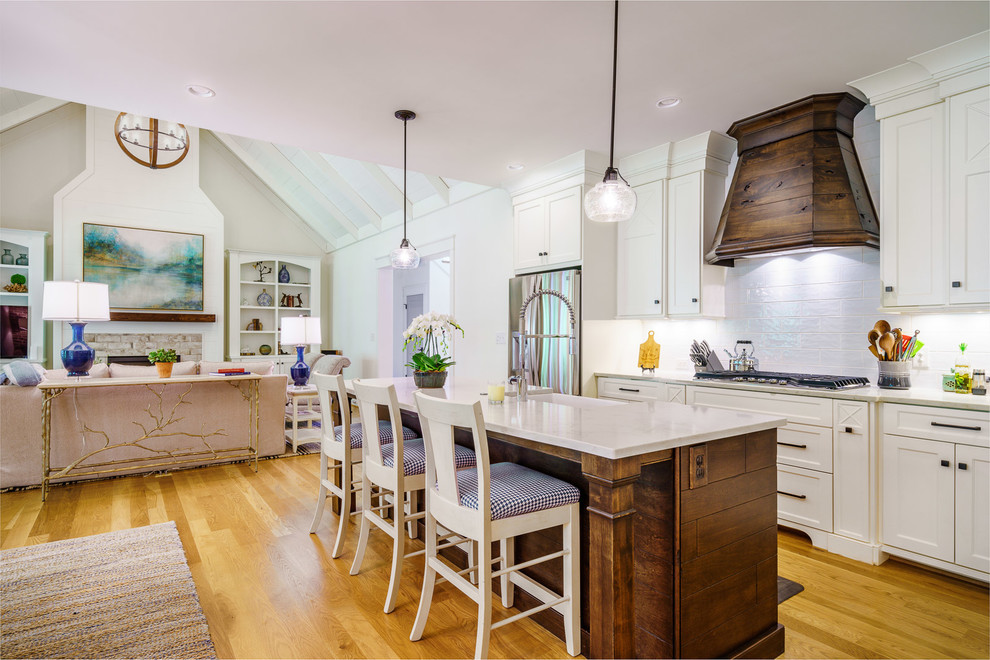 Eat-in kitchen - large transitional u-shaped medium tone wood floor and brown floor eat-in kitchen idea with a farmhouse sink, recessed-panel cabinets, white cabinets, quartz countertops, white backsplash, ceramic backsplash, stainless steel appliances, an island and white countertops