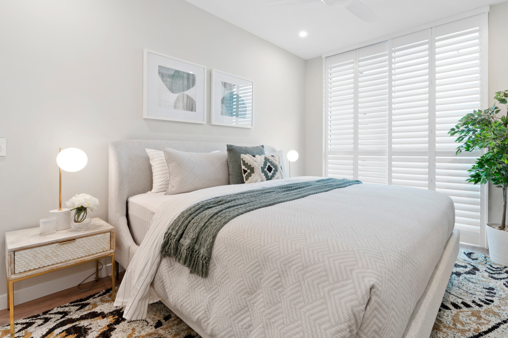 Photo of a beach style master bedroom in Gold Coast - Tweed with white walls, laminate floors and brown floor.