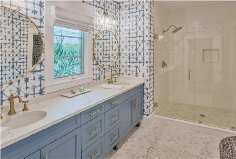 На фото: огромная главная ванная комната в морском стиле с фасадами островного типа, синими фасадами, двойным душем, раздельным унитазом, белой плиткой, керамогранитной плиткой, синими стенами, полом из керамогранита, врезной раковиной, столешницей из искусственного кварца, разноцветным полом, душем с распашными дверями, белой столешницей, тумбой под две раковины, встроенной тумбой и обоями на стенах