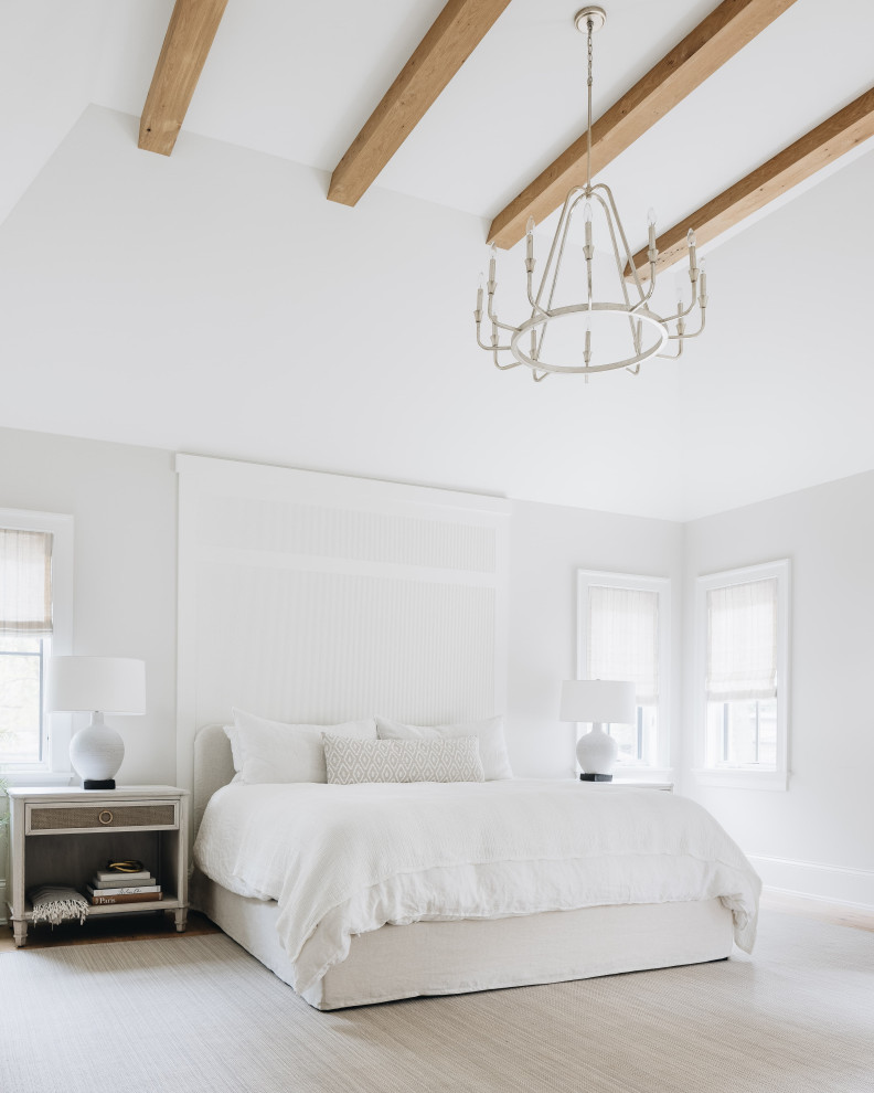 Imagen de dormitorio principal tradicional renovado grande sin chimenea con paredes blancas, suelo de madera clara, suelo beige y vigas vistas