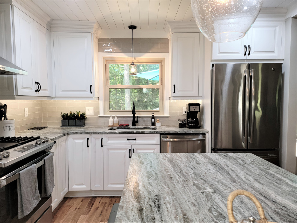 Photo of a large country l-shaped eat-in kitchen in Richmond with an undermount sink, raised-panel cabinets, white cabinets, quartzite benchtops, beige splashback, porcelain splashback, stainless steel appliances, medium hardwood floors, with island, brown floor, grey benchtop and timber.