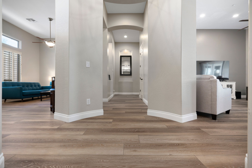 Cette image montre un grand couloir minimaliste avec un mur gris, un sol en vinyl et un sol marron.