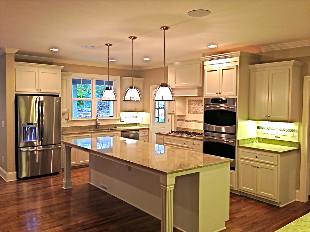 Inspiration for a mid-sized transitional l-shaped medium tone wood floor and brown floor kitchen remodel with an undermount sink, recessed-panel cabinets, white cabinets, subway tile backsplash, stainless steel appliances and an island