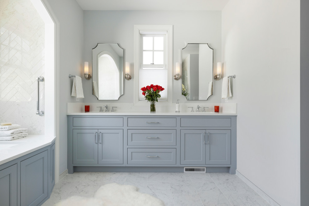 Стильный дизайн: главная ванная комната с фасадами с утопленной филенкой, синими фасадами, полновстраиваемой ванной, душем в нише, раздельным унитазом, белой плиткой, мраморной плиткой, серыми стенами, мраморным полом, врезной раковиной, столешницей из искусственного кварца, белым полом, душем с распашными дверями, белой столешницей, сиденьем для душа, тумбой под две раковины и встроенной тумбой - последний тренд