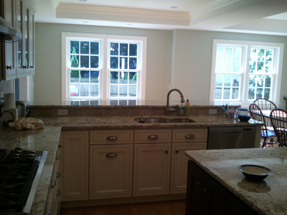 Example of a transitional u-shaped light wood floor eat-in kitchen design in Boston with an undermount sink, shaker cabinets, white cabinets, quartz countertops, beige backsplash, stainless steel appliances and an island