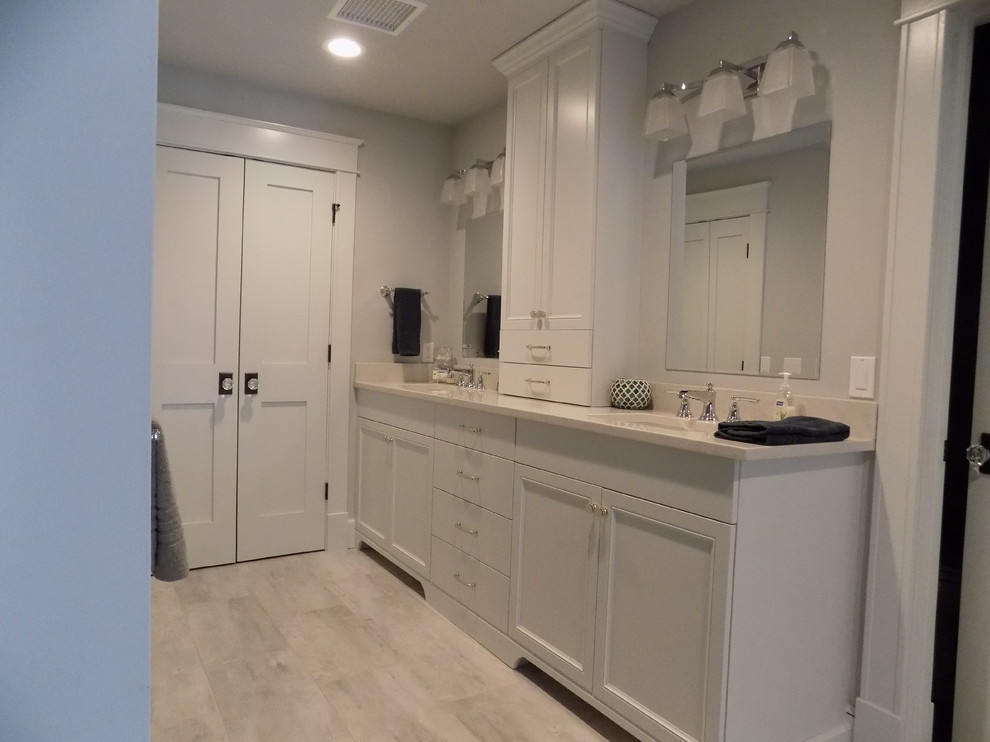 Photo of a mid-sized traditional master bathroom in Other with gray tile, white tile, grey walls, an undermount sink, recessed-panel cabinets, white cabinets and laminate floors.