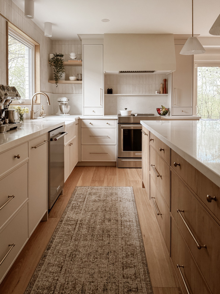 Kitchen - transitional l-shaped light wood floor and beige floor kitchen idea in Toronto with a farmhouse sink, flat-panel cabinets, white cabinets, white backsplash, stainless steel appliances, an island and white countertops