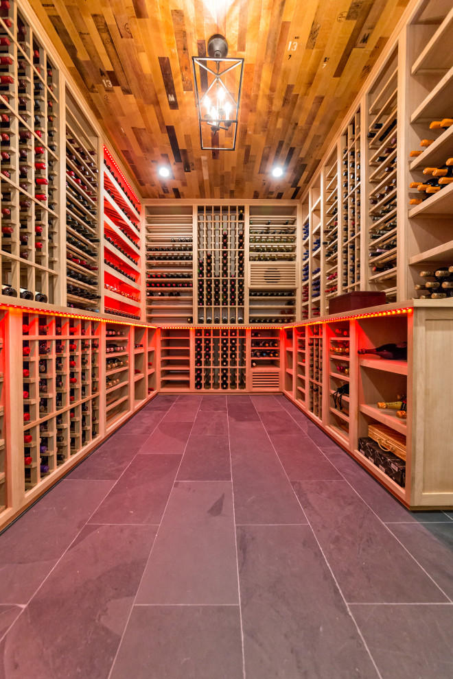 Mid-sized country wine cellar in New York with slate floors, storage racks and black floor.