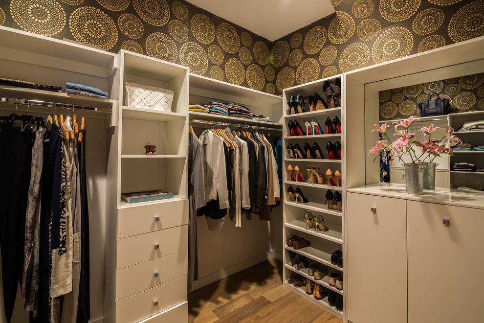 Inspiration for a mid-sized transitional women's walk-in wardrobe in Los Angeles with white cabinets, medium hardwood floors and flat-panel cabinets.