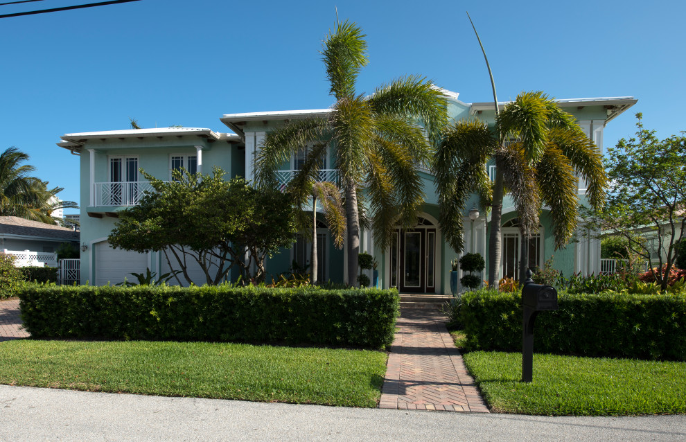 Foto della villa grande blu tropicale a due piani con rivestimento in stucco, copertura in metallo o lamiera e tetto bianco