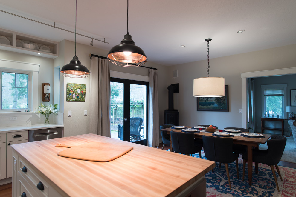 Example of a mid-sized transitional l-shaped medium tone wood floor and brown floor eat-in kitchen design in Seattle with an undermount sink, recessed-panel cabinets, white cabinets, quartz countertops, white backsplash, ceramic backsplash, stainless steel appliances, an island and white countertops
