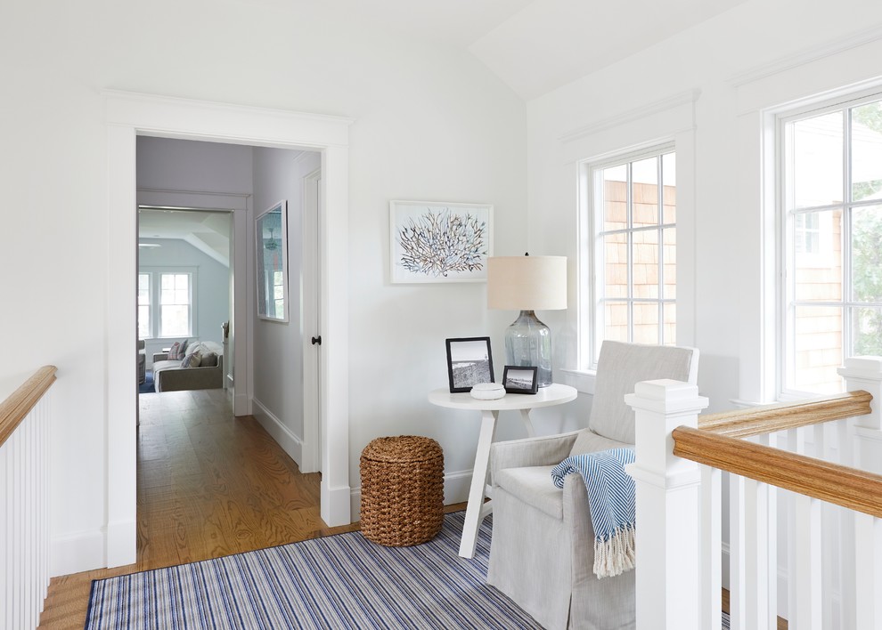 Photo of an expansive beach style hallway in New York with white walls and medium hardwood floors.