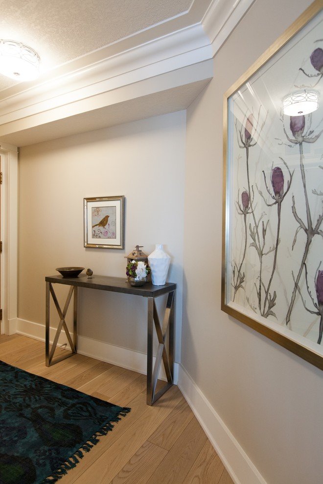 This is an example of a small transitional foyer in Edmonton with beige walls and light hardwood floors.