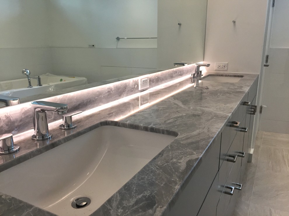This is an example of a contemporary master bathroom in Houston with an undermount sink and marble benchtops.